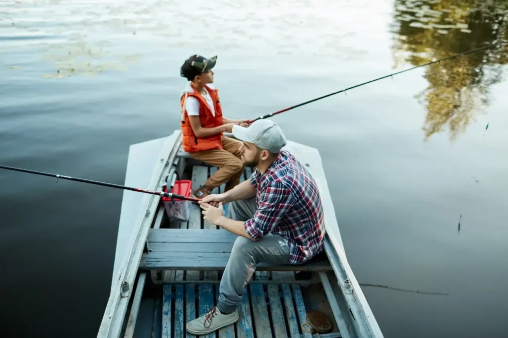 A father and son enjoy a peaceful fishing trip on a small boat, casting their lines into a calm lake—a perfect bonding experience with essential fishing gear.