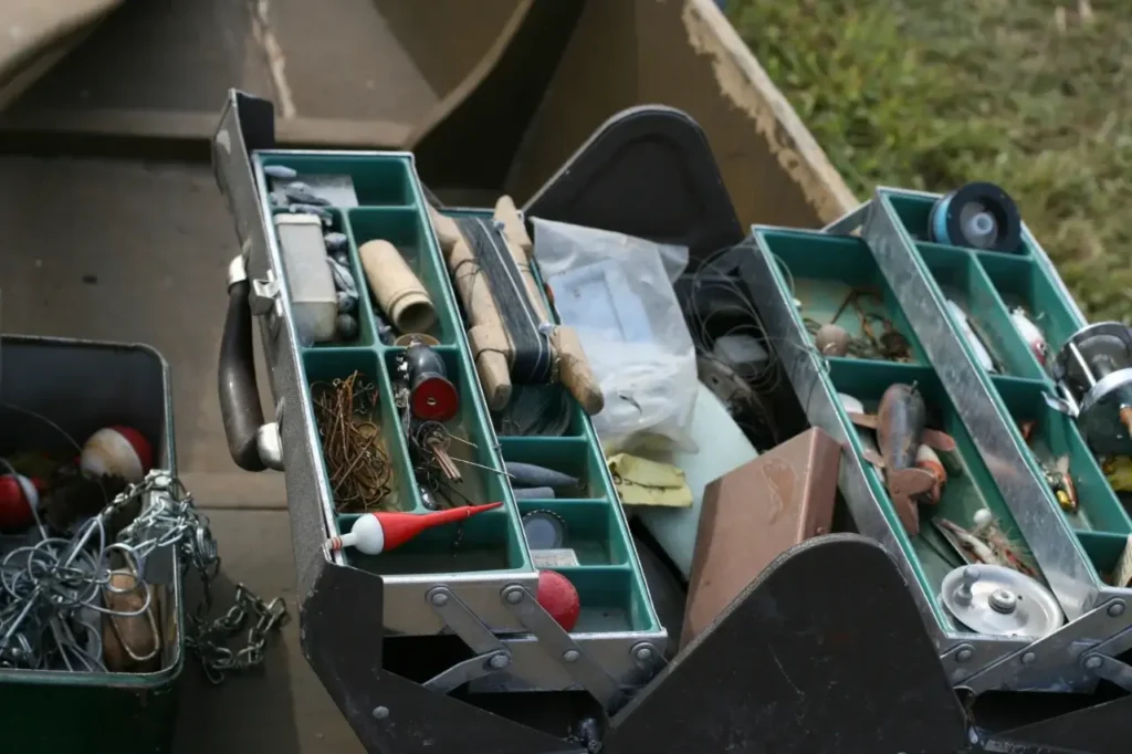 A fully stocked tackle box filled with essential fishing tools, including hooks, lures, fishing line, and pliers, ideal for a well-prepared angler.