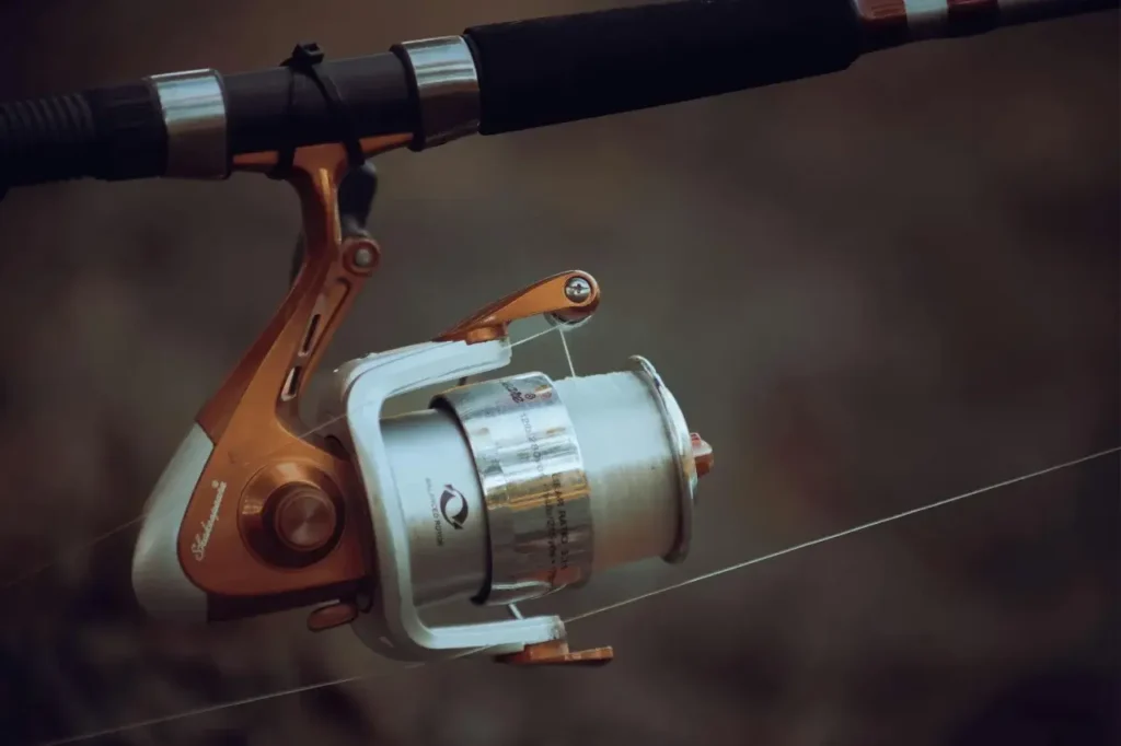 A close-up of a spinning reel mounted on a fishing rod, spooled with a strong fishing line, highlighting essential fishing gear for beginners and pros.